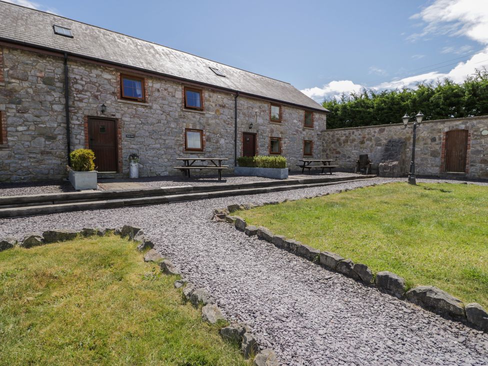 An outdoor area with a stone building and seating at Beudy Bach in Dolwen near Abergele