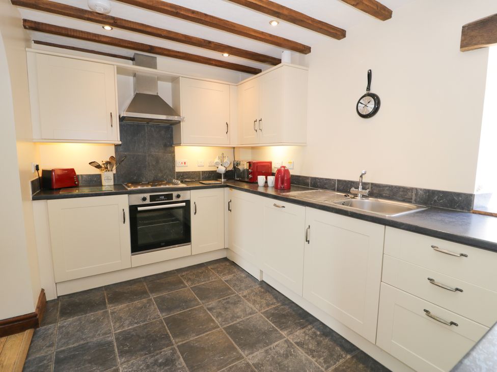 A kitchen with cabinets, a sink, and appliances at Beudy Bach Dolwen near Abergele