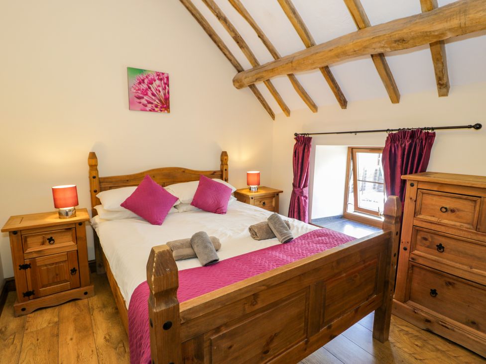 A bedroom with a wooden bed and furniture at Beudy Bach Dolwen near Abergele