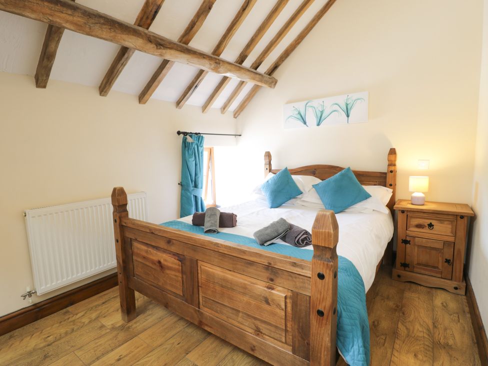A bedroom with a wooden bed and bedside table at Beudy Bach Dolwen near Abergele