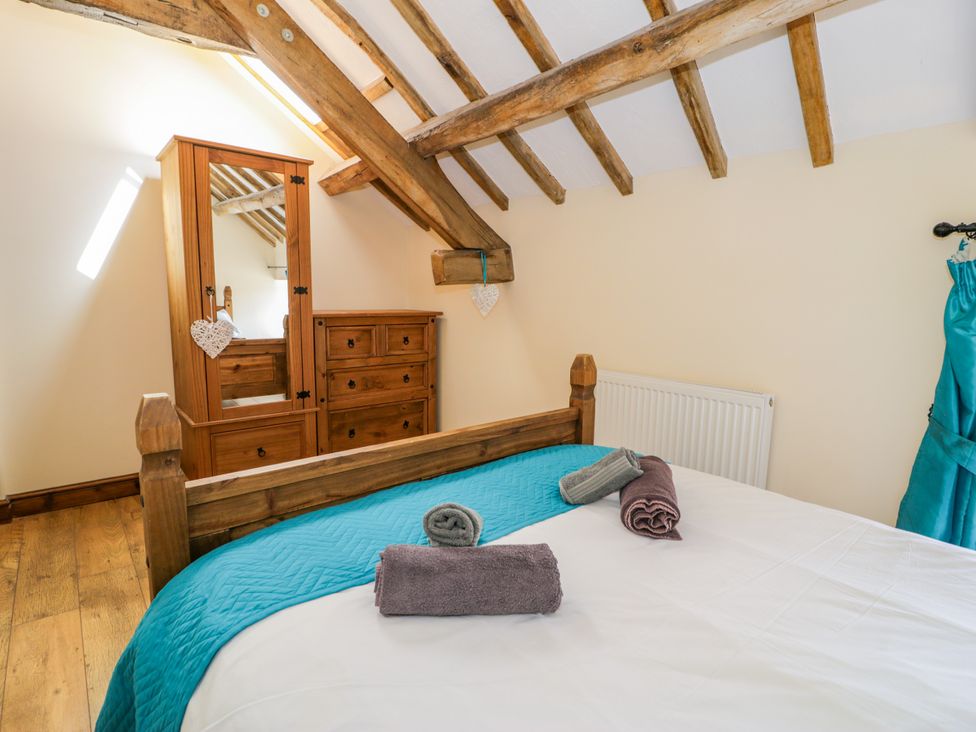 A bedroom with a wooden bed and dresser at Beudy Bach in Dolwen near Abergele