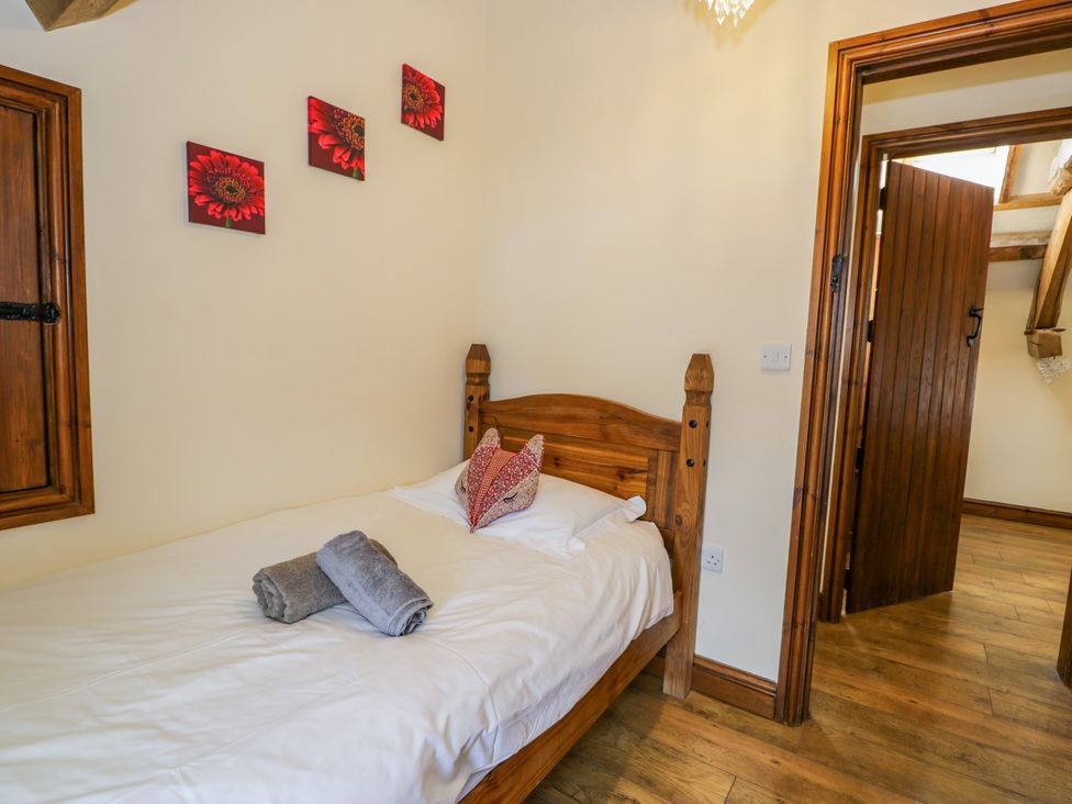 A bedroom with a single bed and wall art at Beudy Bach, Dolwen near Abergele