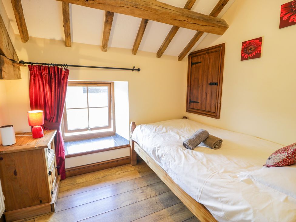 A bedroom with a bed and window at Beudy Bach in Dolwen near Abergele