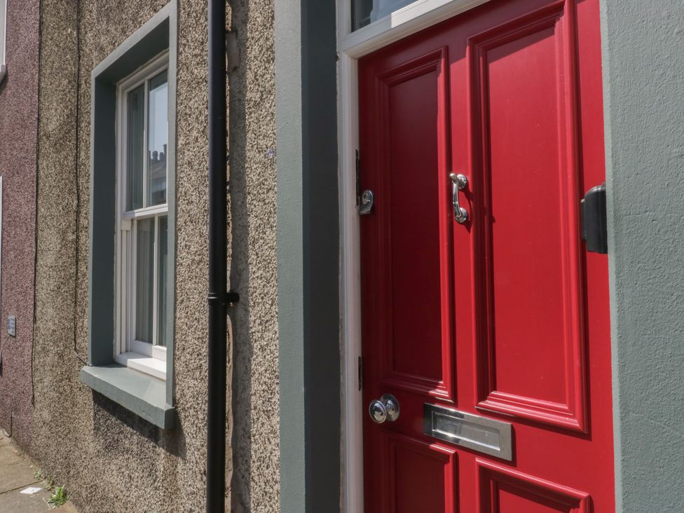 A red door with a handle and letterbox next to a window at Number Thirty-Nine in Ulverston