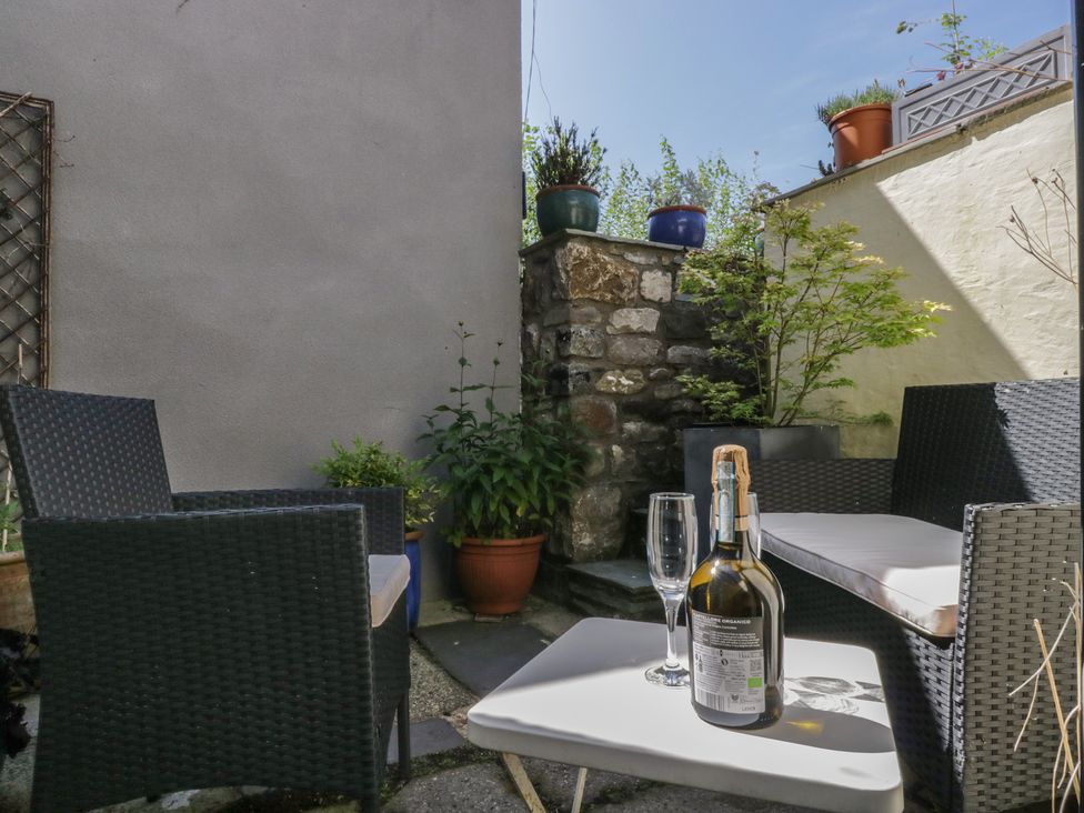 A wine bottle and glasses on a table with chairs in an outdoor space at Number Thirty-Nine Ulverston