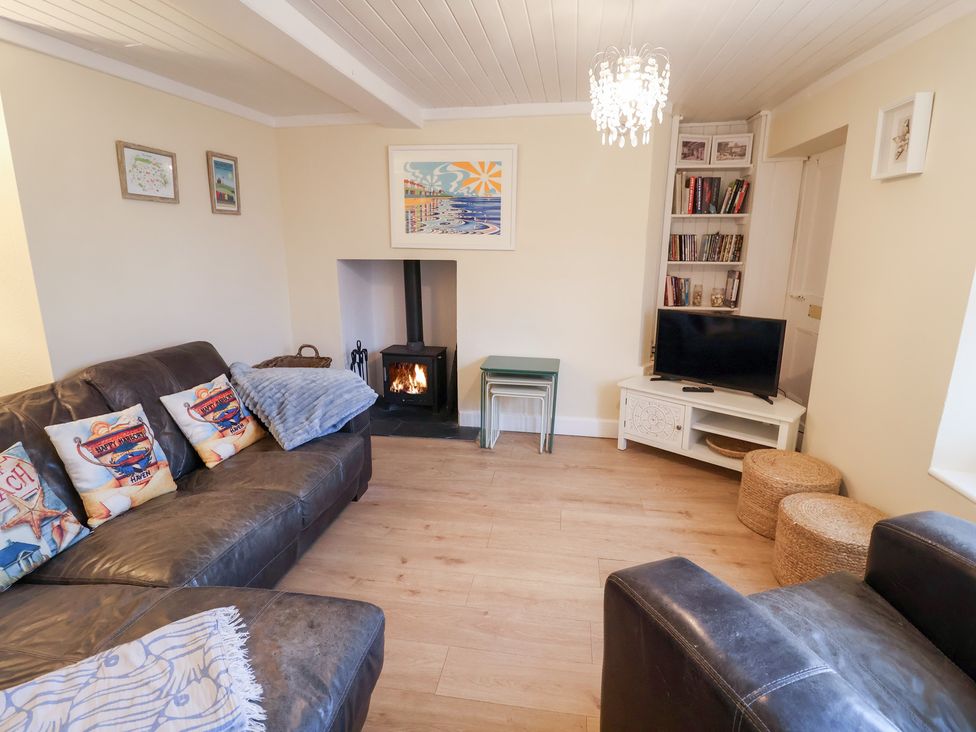 A living room with a fireplace and a television at Cobbler's Cottage in Mundesley