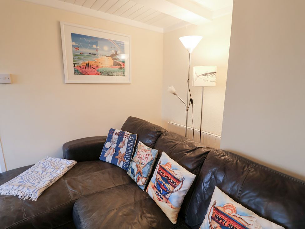 A living room with a sofa and artwork at Cobbler's Cottage in Mundesley