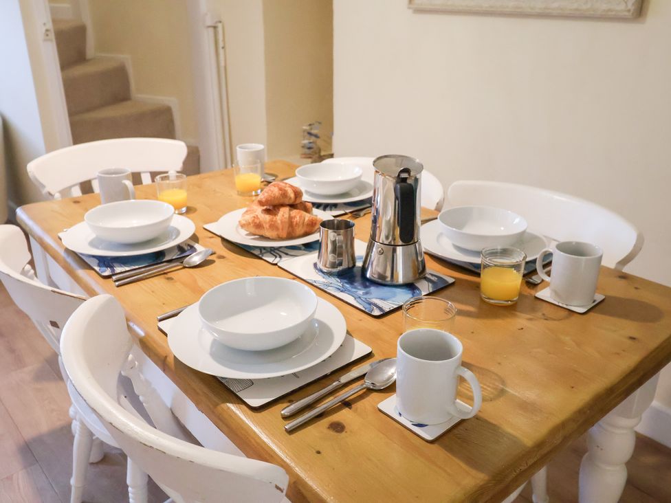 A dining table set with mugs and croissants at Cobbler's Cottage Mundesley
