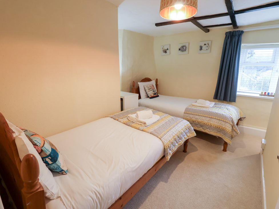 A bedroom with two beds and a window at Cobbler's Cottage in Mundesley