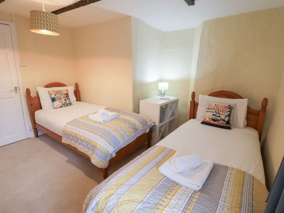 A bedroom with two single beds and a nightstand at Cobbler's Cottage in Mundesley