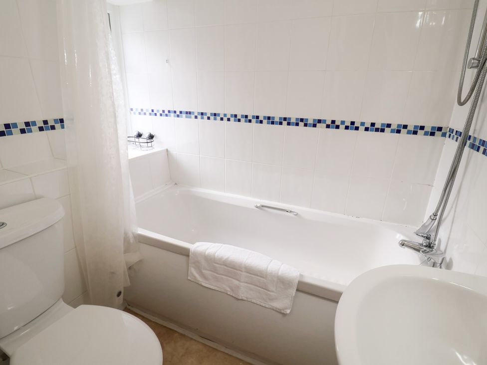 A bathroom with a bathtub and a toilet at Cobbler's Cottage Mundesley