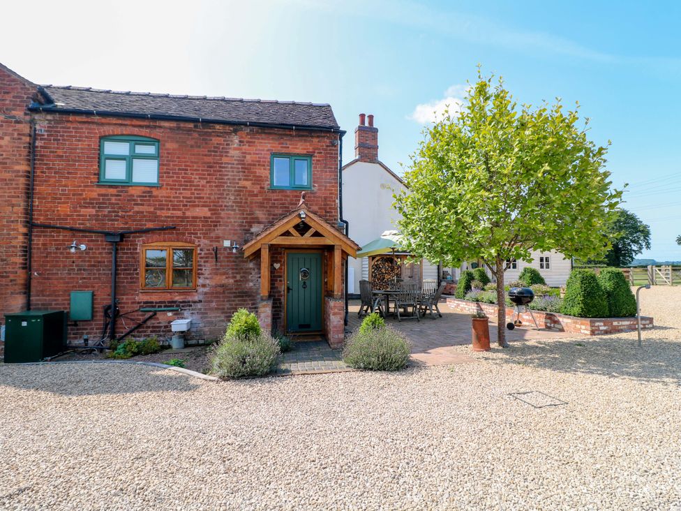 A house exterior with seating area and tree at Bellamour End Cottage Rugeley