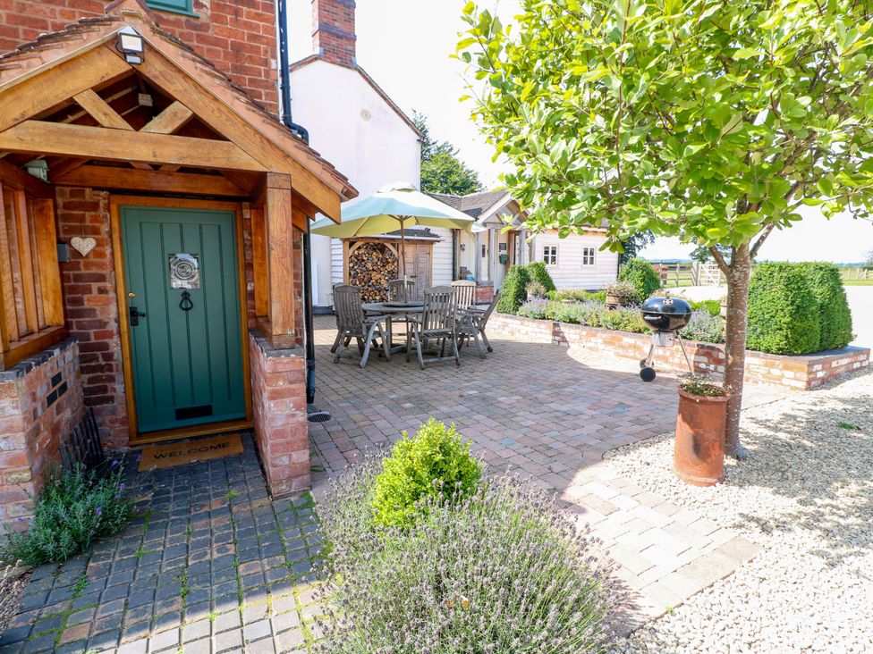 A garden with a table and chairs under an umbrella at Bellamour End Cottage in Rugeley