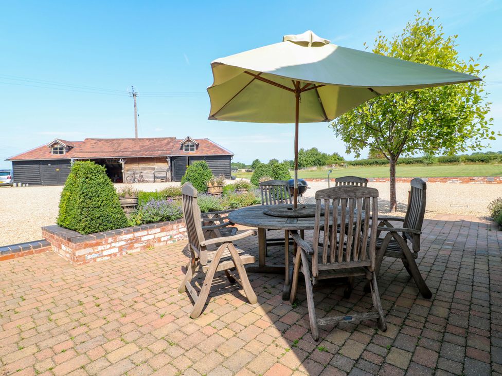 A dining area with a wooden table and chairs under an umbrella at Bellamour End Cottage Rugeley