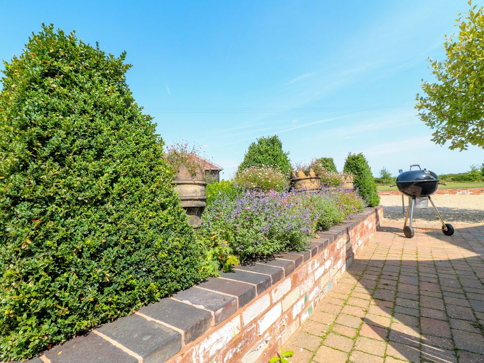 A garden with hedges flowers and a barbecue at Bellamour End Cottage Rugeley
