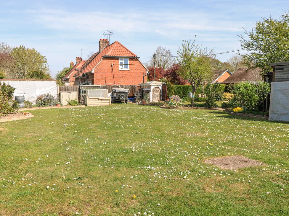 A backyard garden with grass trees and bushes behind a brick house at Lillies Pad in Methwold near Feltwell