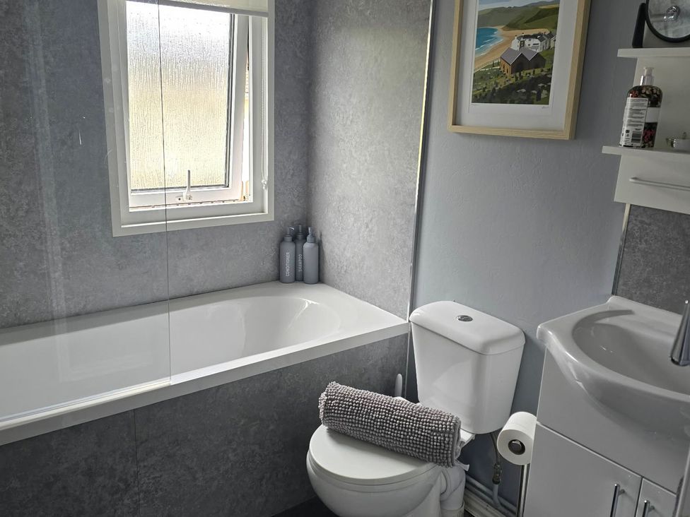 A bathroom with a bathtub and sink at Caban Tywod Abersoch