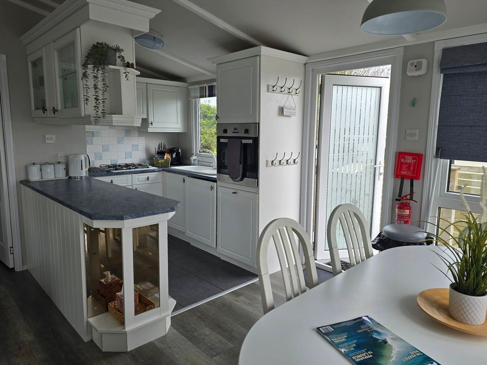 A kitchen with cabinets and an island at Caban Tywod in Abersoch