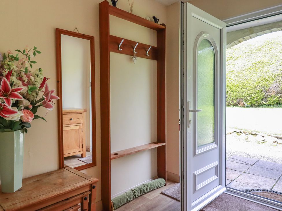 A hallway with a coat rack and mirror at Underlanes in Boscastle