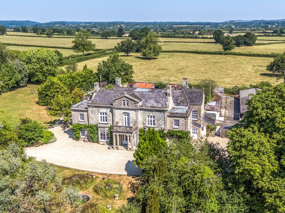 An aerial view of a large house surrounded by fields and trees at Milton Manor in Milton On Stour