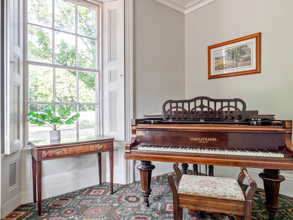 A music room with a piano and table at Milton Manor in Milton On Stour