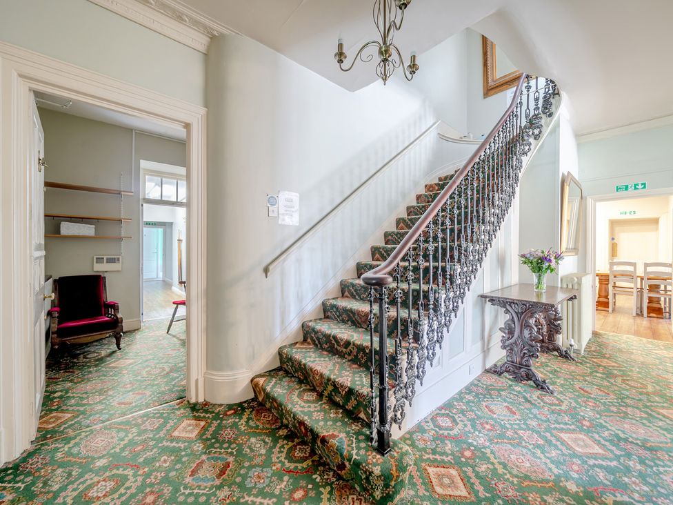 A hallway featuring a staircase and a chair at Milton Manor in Milton On Stour