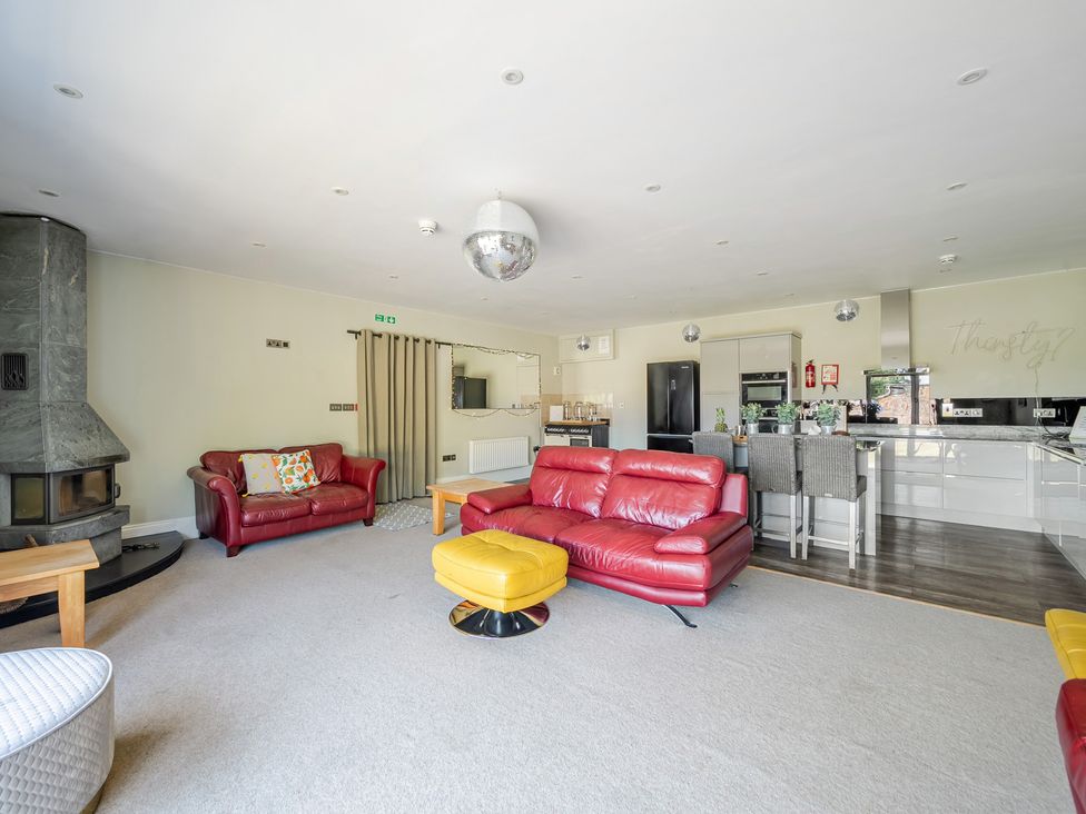 A living room with a sofa and kitchen area at Milton Manor in Milton On Stour