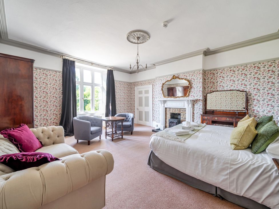 A bedroom with a bed, sofa and seating area at Milton Manor in Milton On Stour