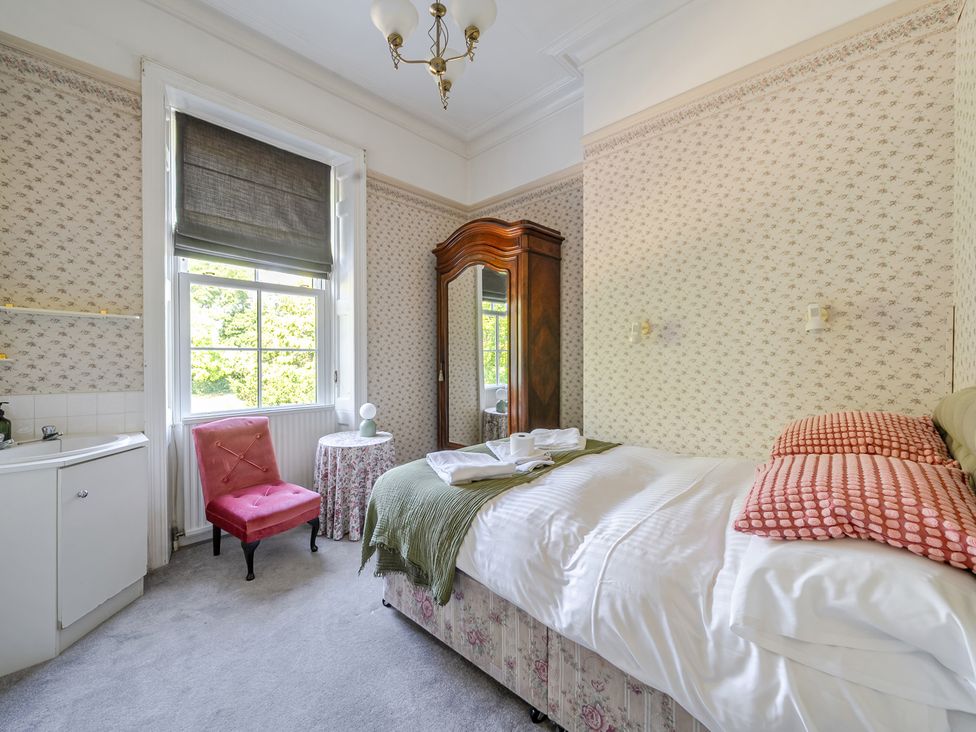 A bedroom with a bed and a chair at Milton Manor in Milton On Stour