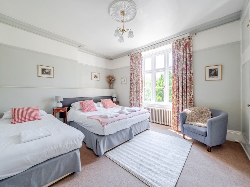 A bedroom with two beds and a chair at Milton Manor in Milton On Stour