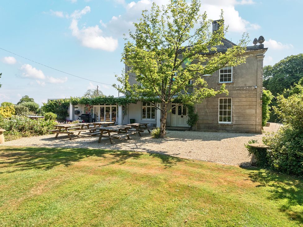 A house with picnic tables and a tree in the garden at Milton Manor in Milton On Stour