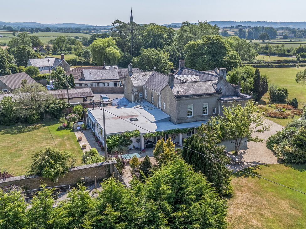 An outdoor view of a house with garden and trees at Milton Manor in Milton On Stour