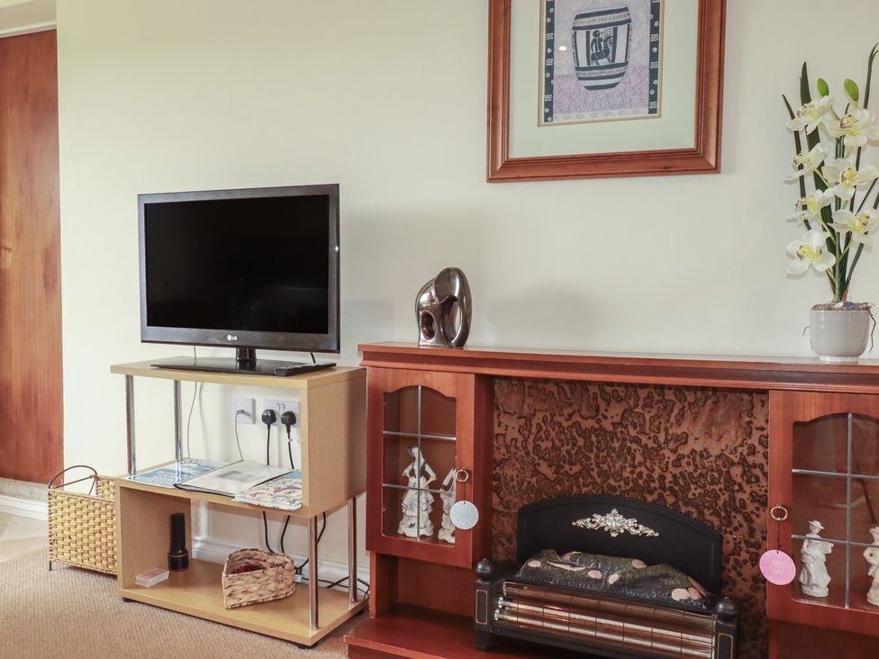 A living room with a television and decorative items at Little Lanes in Boscastle