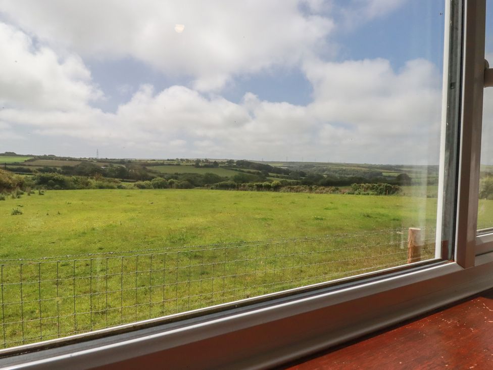A view of grassland and hills from a window at Little Lanes in Boscastle