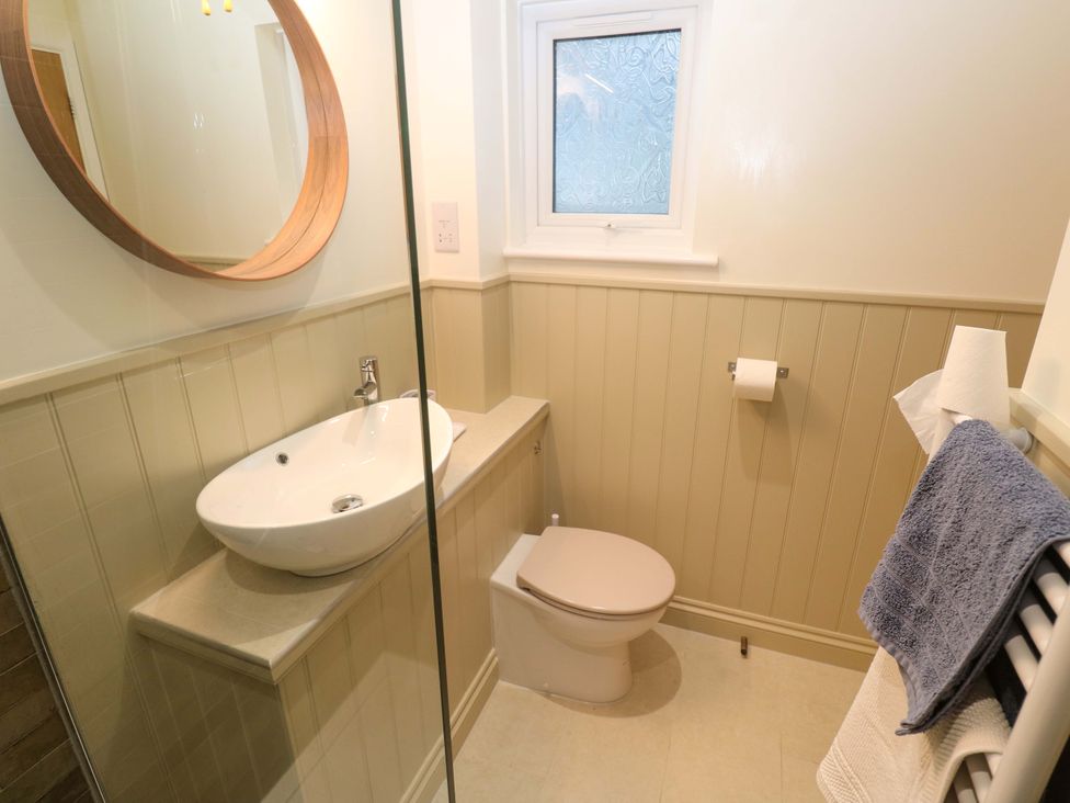 A bathroom with a sink, toilet, and mirror at The Poop Deck in Coverack