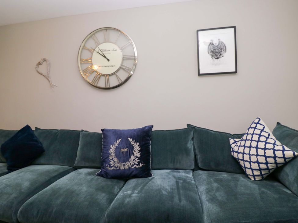 A living room with a clock on the wall and a sofa at Bishop Fell in Newby Bridge