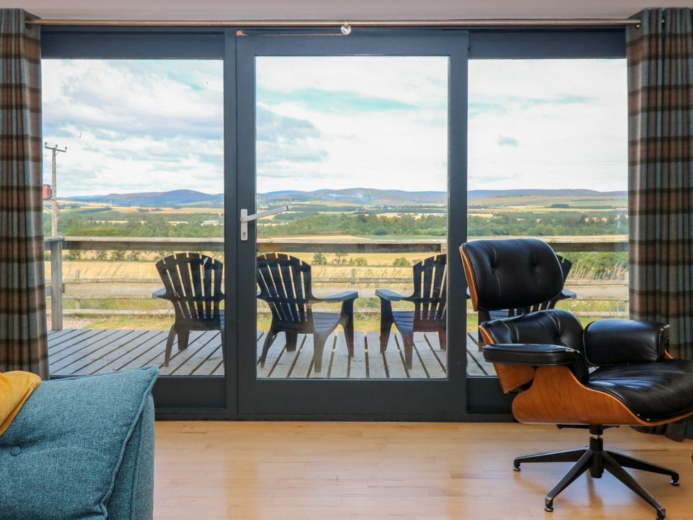 A living room with a glass door and chairs at Whitehouse Woodwrae in Aberlemno near Forfar