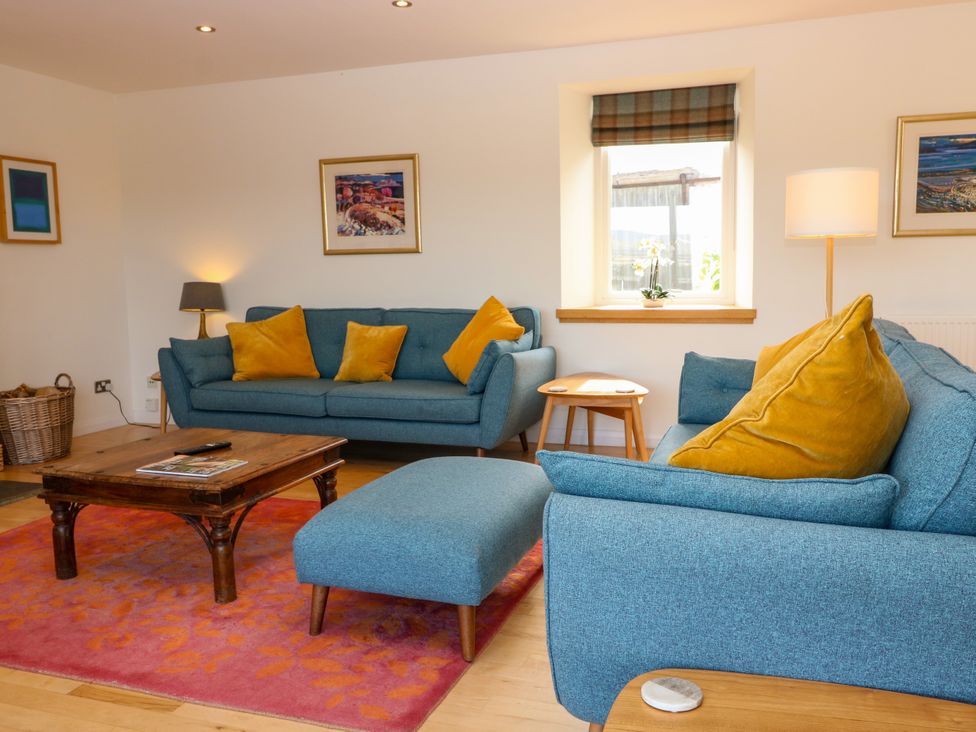 A living room with blue sofas and a wooden coffee table at Whitehouse Woodwrae Aberlemno near Forfar