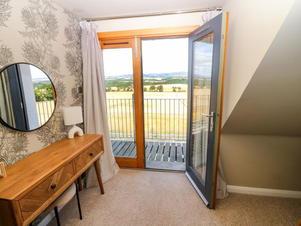 A bedroom with a console table and a balcony door at Whitehouse Woodwrae Aberlemno near Forfar