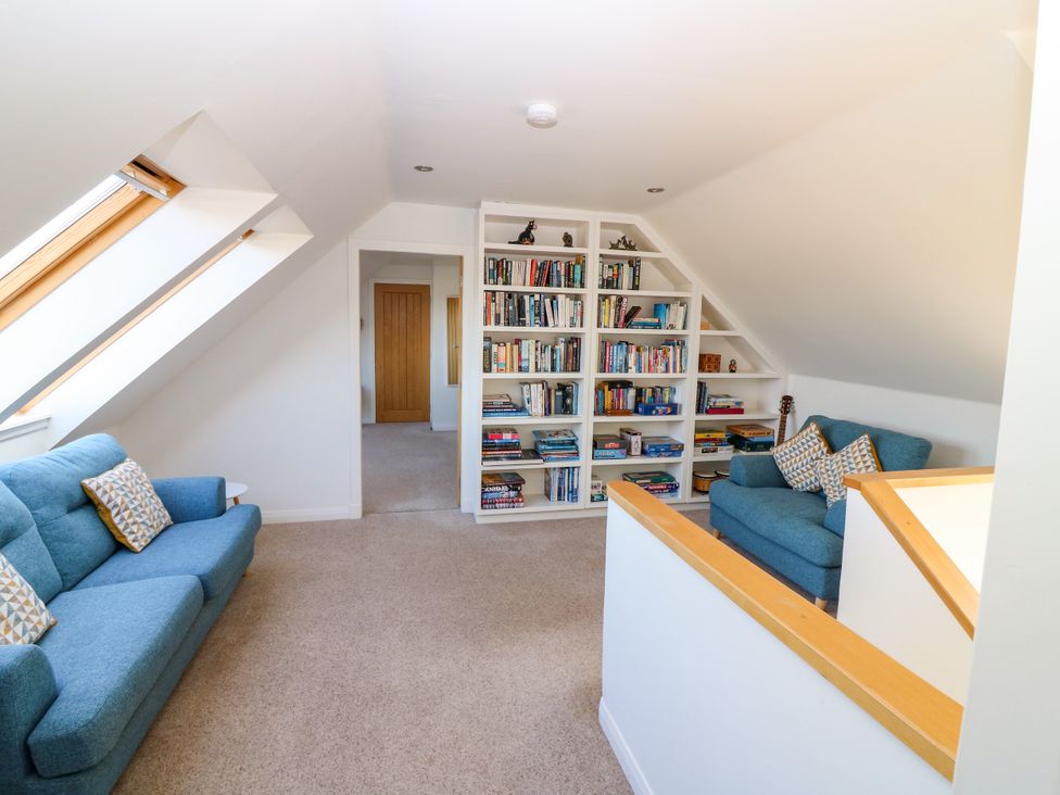 A snug with blue sofas and a bookshelf at Whitehouse Woodwrae near Forfar