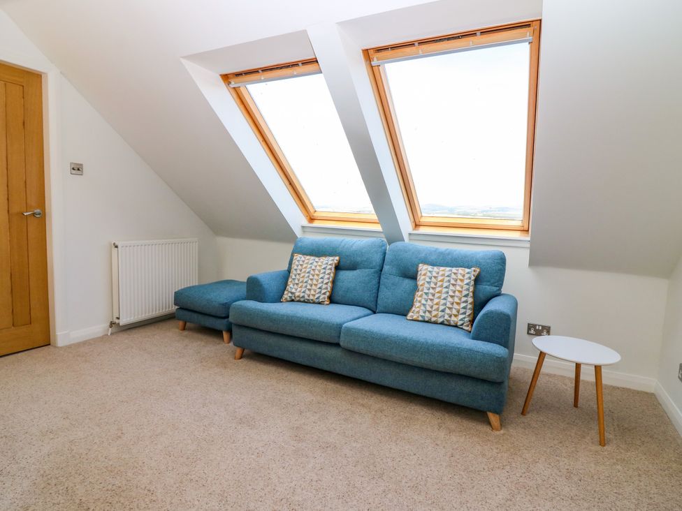 A living room with a blue sofa and window at Whitehouse Woodwrae Aberlemno near Forfar
