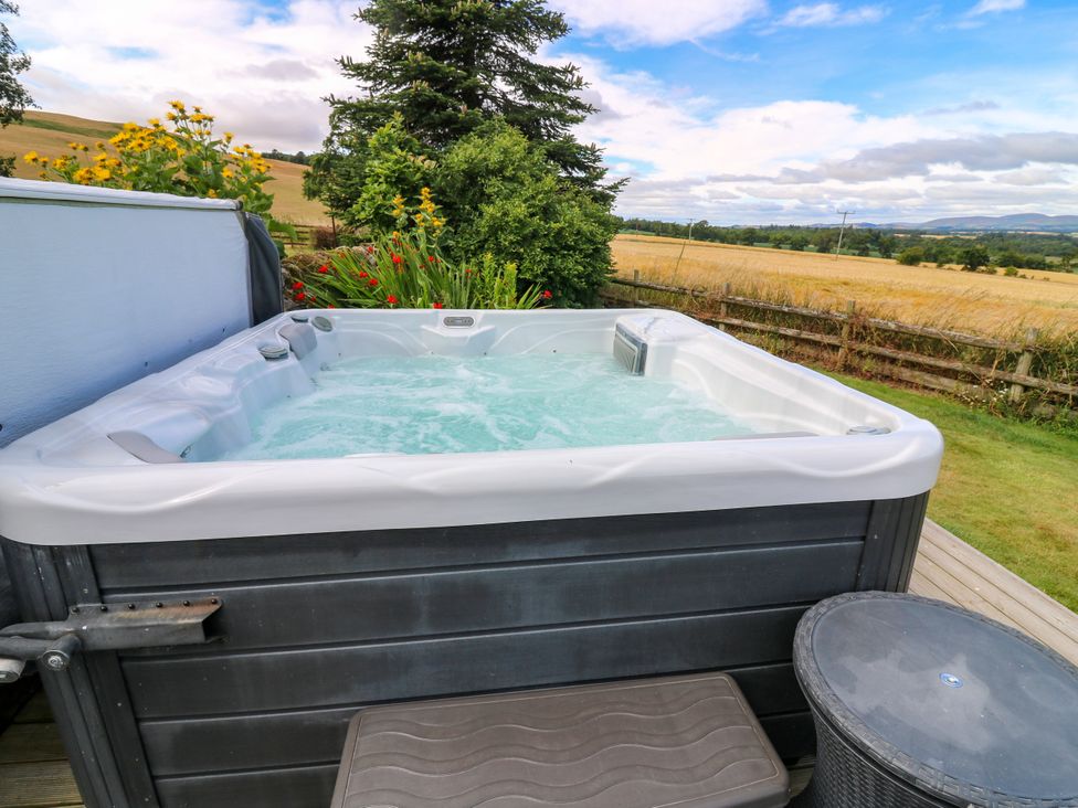 A hot tub on a wooden deck with garden plants at Whitehouse Woodwrae Aberlemno near Forfar
