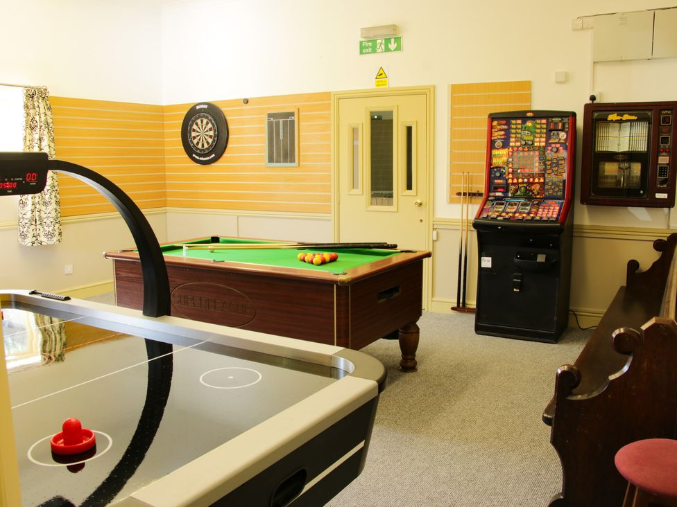 A game room with an air hockey table a pool table a dartboard a slot machine and a wooden bench at The Boars Head Pub Bishop's Castle