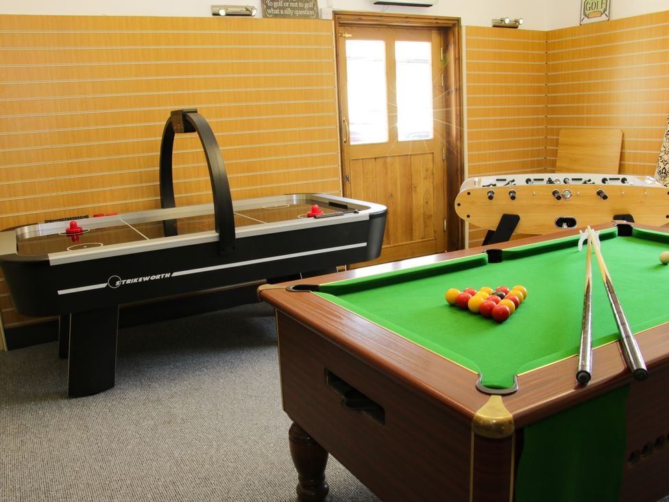 A game room with a pool table, air hockey table, and foosball table at The Boars Head Pub in Bishops Castle