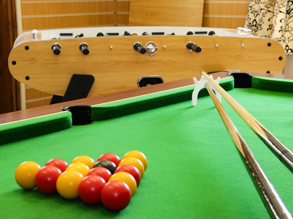 A pool table with balls and cues and a foosball table in the background at The Boars Head Pub in Bishops Castle