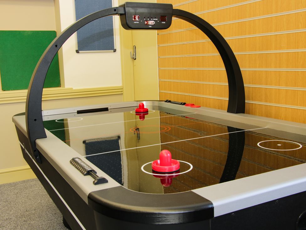 An air hockey table with two red strikers in a room with wooden paneling on the wall at The Boars Head Pub in Bishop's Castle