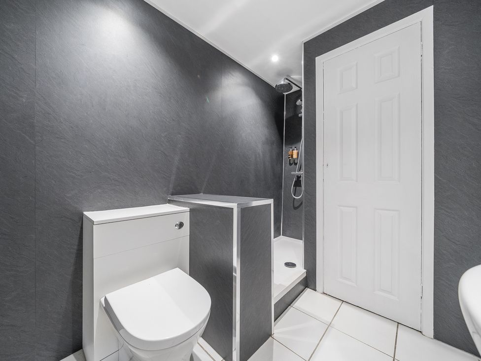 A bathroom with a toilet a walk in shower and a white door at The Boars Head Pub in Bishops Castle