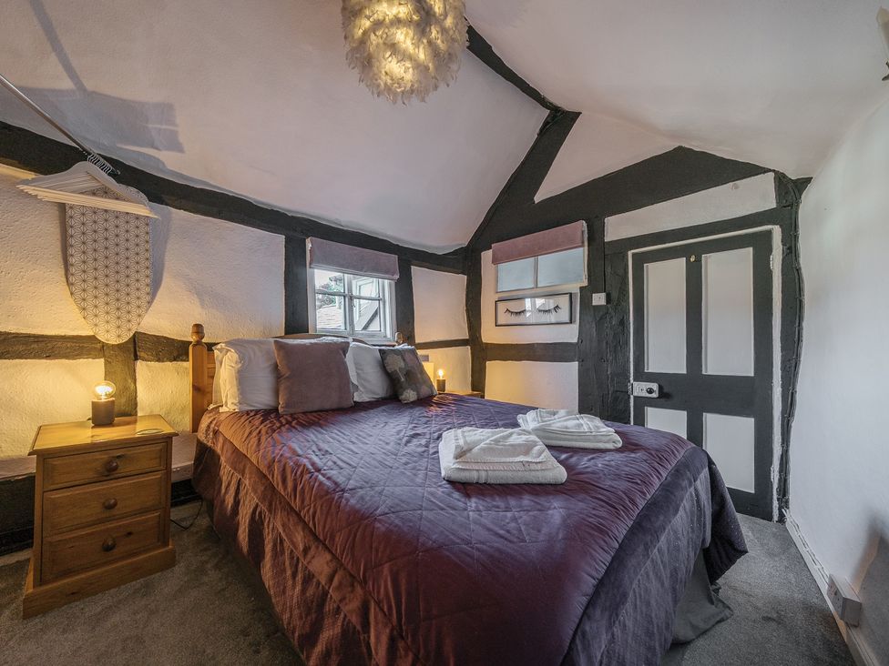 A bedroom with a double bed bedside tables and a door with black timber beams on the walls at The Boars Head Pub in Bishops Castle