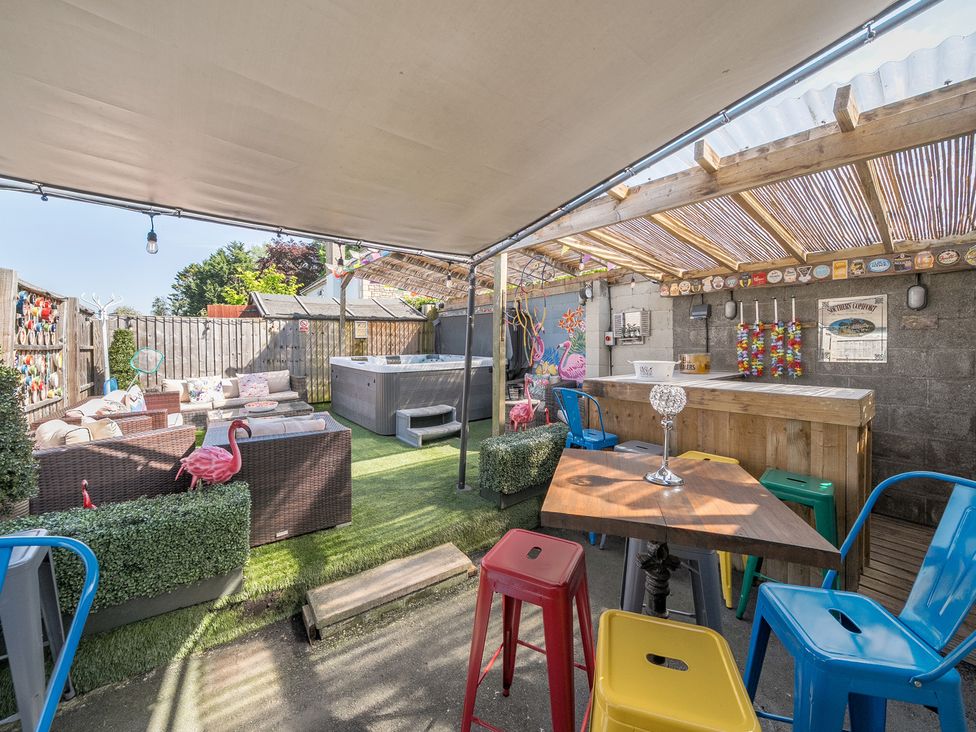 An outdoor seating area with colorful chairs tables a wooden bar and a hot tub at The Boars Head Pub in Bishops Castle
