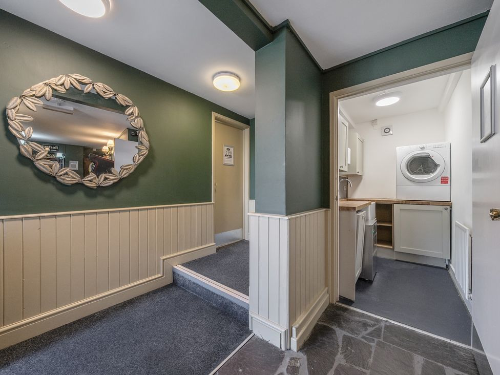 A hallway with green and white walls a mirror on the wall and an adjoining laundry room with a washing machine at The Boars Head Pub in Bishops Castle